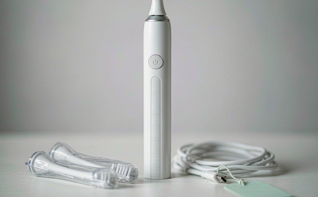 Rechargeable sonic electric toothbrush with replacement brush heads photographed in a clean B2B studio setting on a light grey background